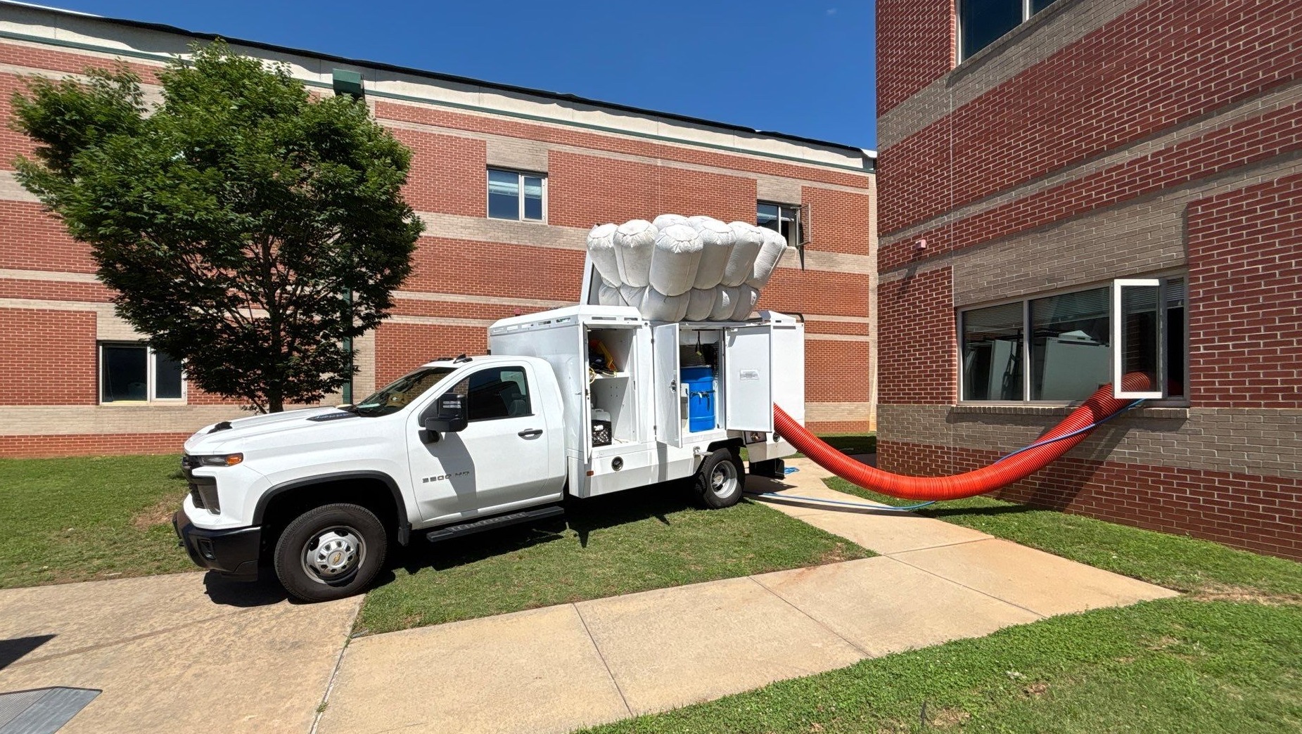IAQ Restoration gas-powered vacuum duct truck on the job, suction hose under negative pressure