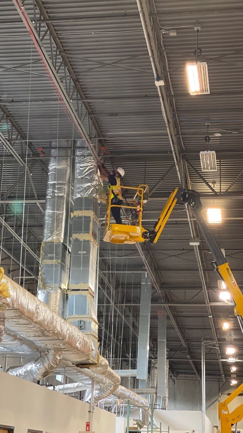 Boom lift duct cleaning at an industrial warehouse roof deck
