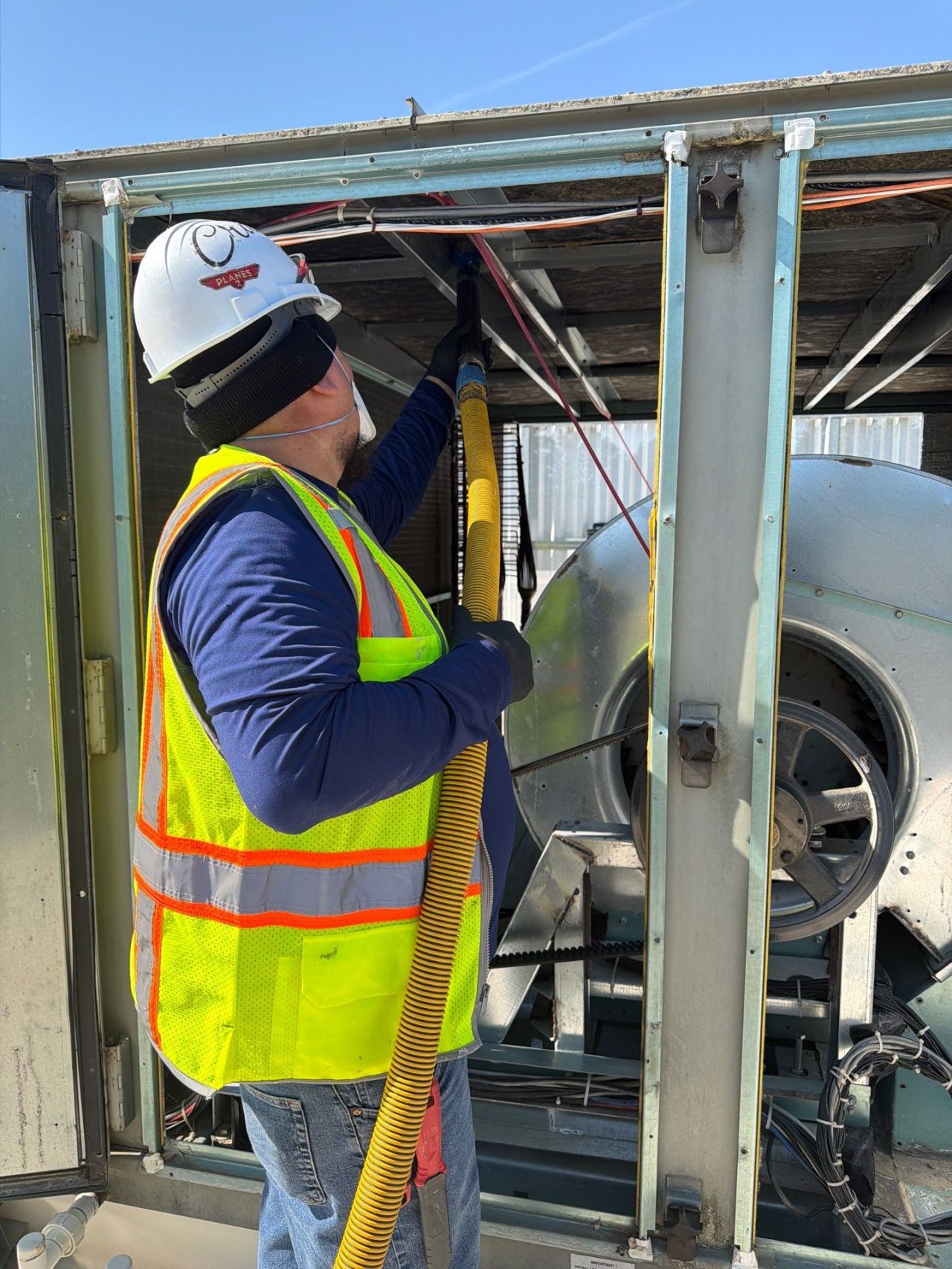 Technician vacuum-extracting an RTU blower compartment