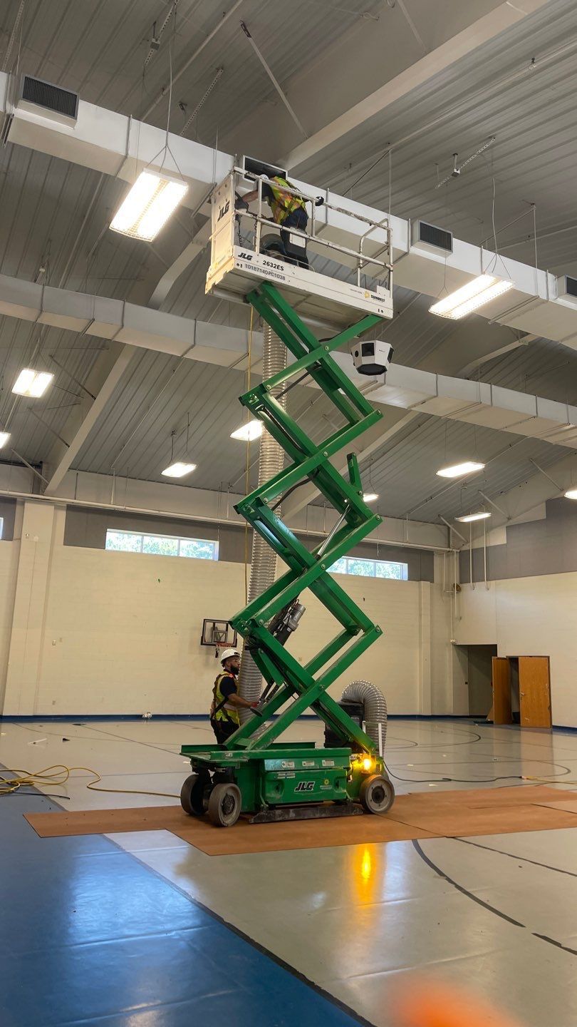 Scissor lift duct cleaning at a school gymnasium ceiling